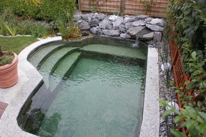 Wasserfall im Naturpool mit einem Natursteinblock